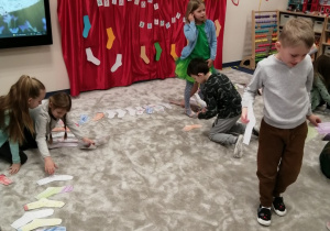 23 dzieci układają kolorowe skarpetki na dywanie.jpg
